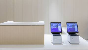 A reception desk with a wooden sign, two digital displays, and a white counter.