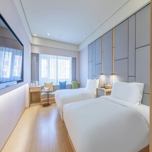 A hotel room with two beds, a desk, a chair, a small table, and a window with curtains. - Ji Hotel (Beijing)
