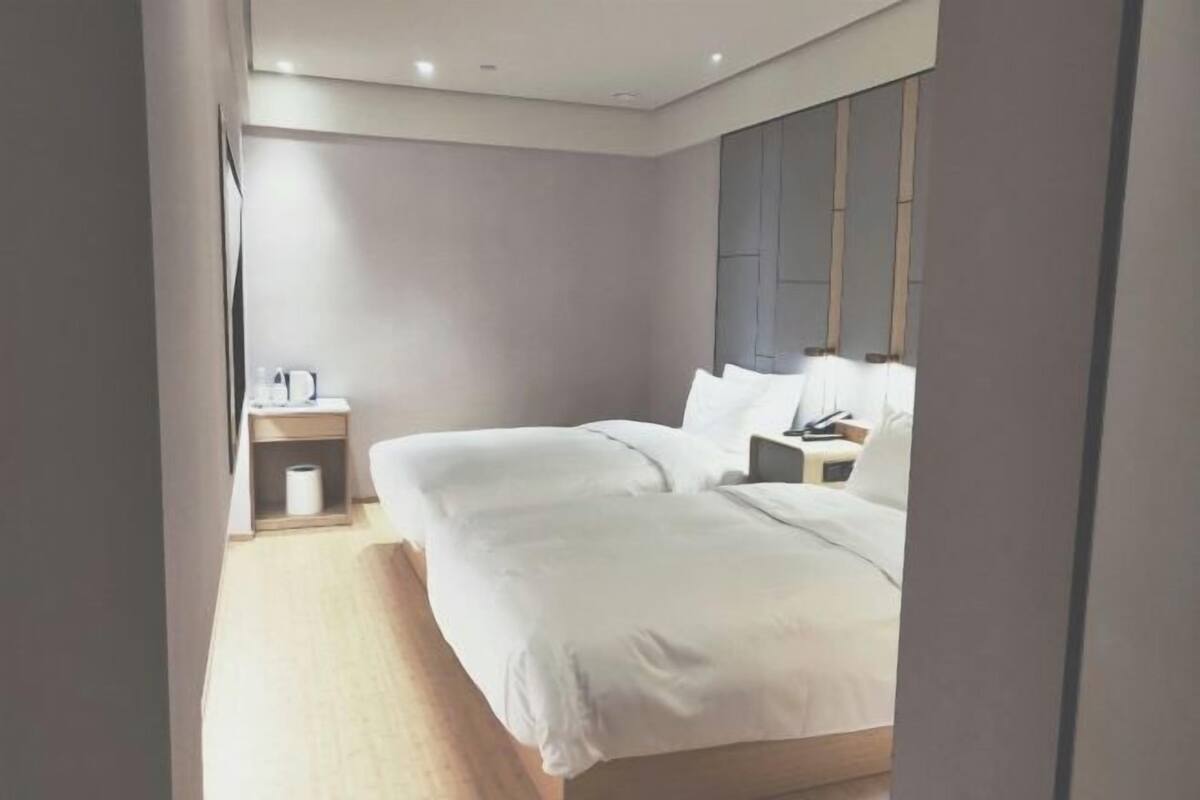 A modern hotel room with a large bed, bedside tables, and a headboard with storage.