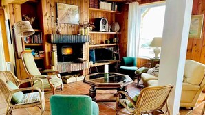 Ein gemütliches Wohnzimmer mit Kamin, Korbmöbeln und Bücherregal.