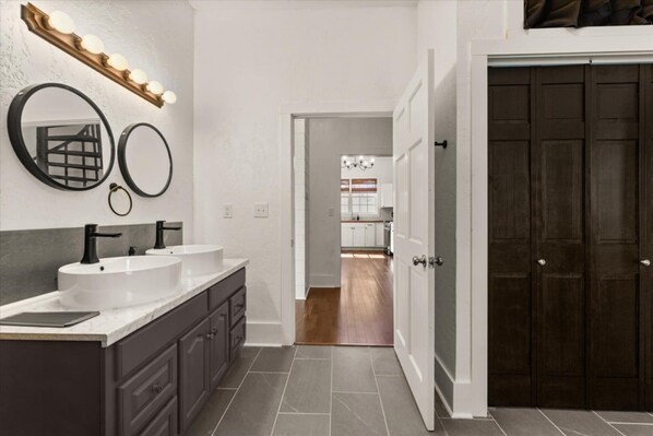 Un baño moderno con dos lavabos, tocador y espejo con iluminación.
