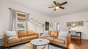 A modern living room with two leather sofas, a round coffee table, and a ceiling fan.