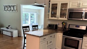 Una cocina con una isla central, electrodomésticos de acero inoxidable y un comedor con sillas y una mesa.