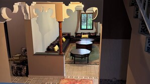 Vue depuis un balcon sur un salon comprenant un ensemble de canapés, une table basse et un tapis à motifs.