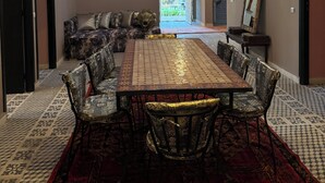 Un coin repas avec une longue table et des chaises, un canapé et un miroir décoratif.