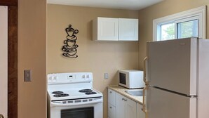A compact kitchen with white appliances, including a stove and refrigerator, and a microwave. - 3-bedroom Wasaga Beach Walk to beach Free Parking Free Wifi (Wasaga Beach)