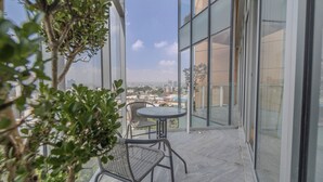 A balcony with a table and chairs, large windows offering a city view, and a potted plant. - Icon Cibeles heart of La Roma (Mexico City)
