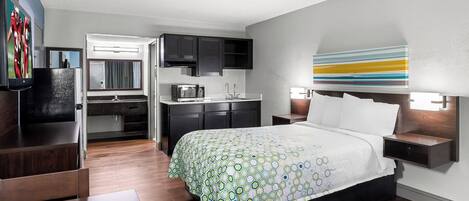 Una habitación de hotel moderna con una cama, un escritorio y un kitchenette.