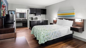 Una habitación de hotel moderna con una cama, un escritorio y un kitchenette.