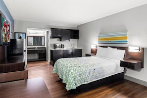 A modern hotel room with a bed, a desk, and a kitchenette. - HomeTowne Studios by Red Roof Richmond - Airport/Sandston (Sandston)