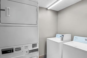 Una sala de lavandería con lavadoras y secadoras apiladas, un panel de control y una secadora Whirlpool.