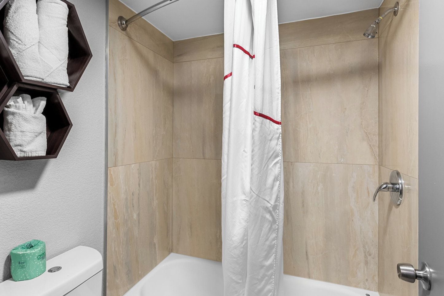 A modern bathroom with a shower, toilet, and towel storage.