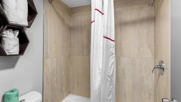 A modern bathroom with a shower, toilet, and towel storage.