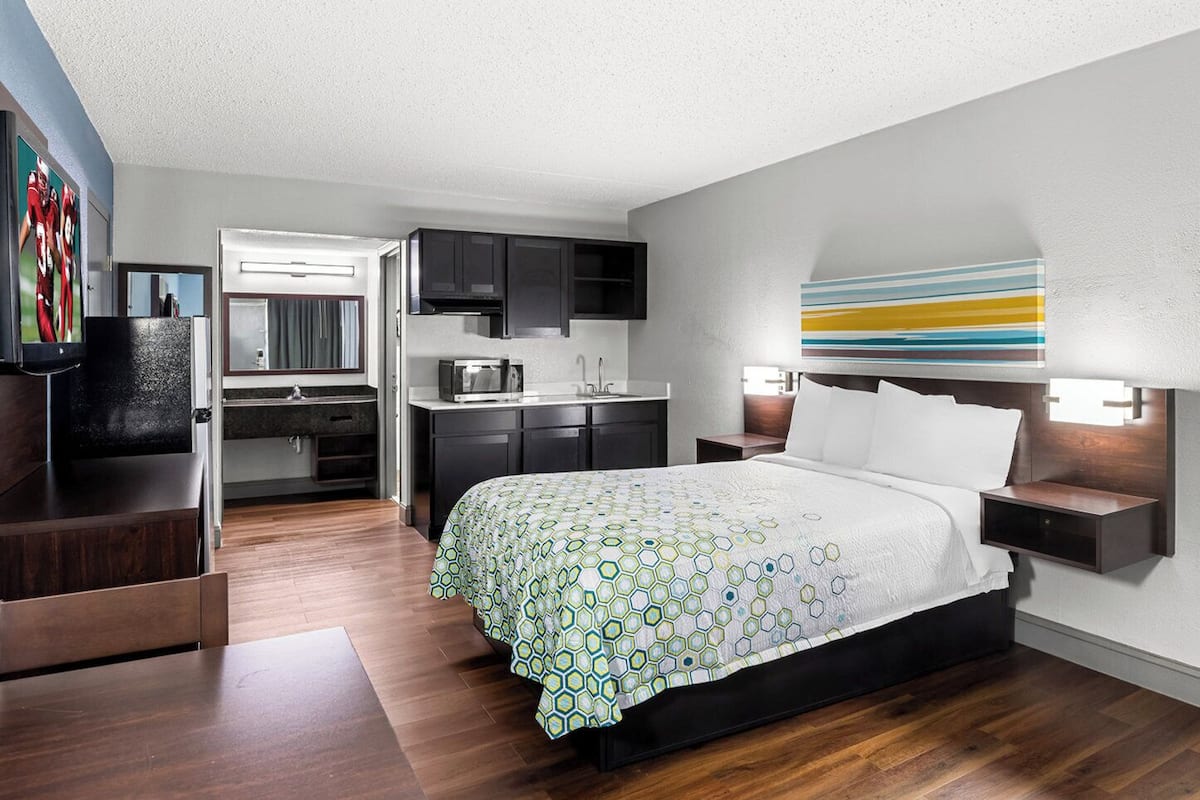 Una habitación de hotel moderna con una cama, un escritorio y un kitchenette.