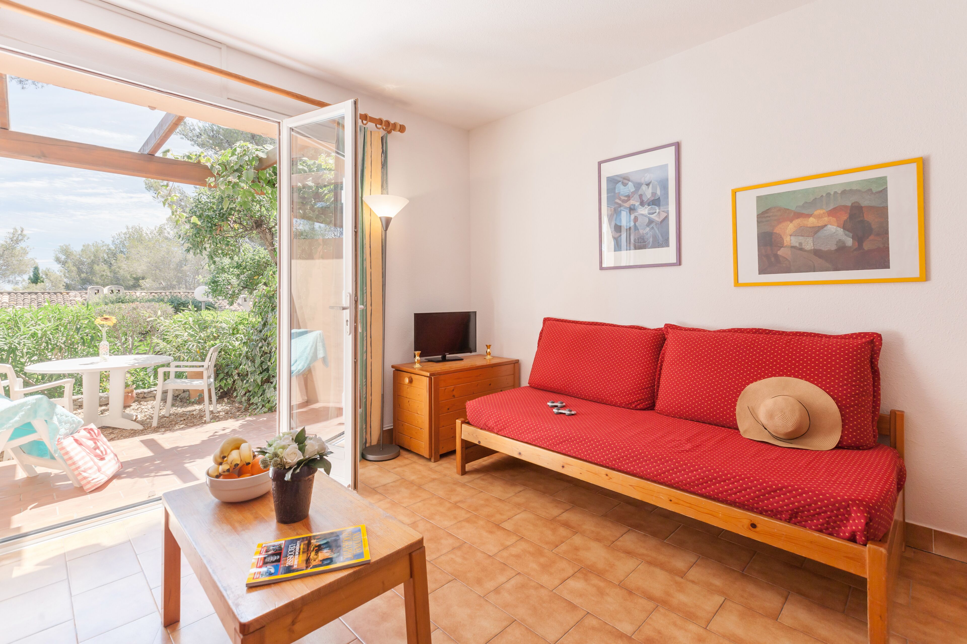 A cozy room with a wooden sofa, a TV, and a dining table with a bowl of fruit.