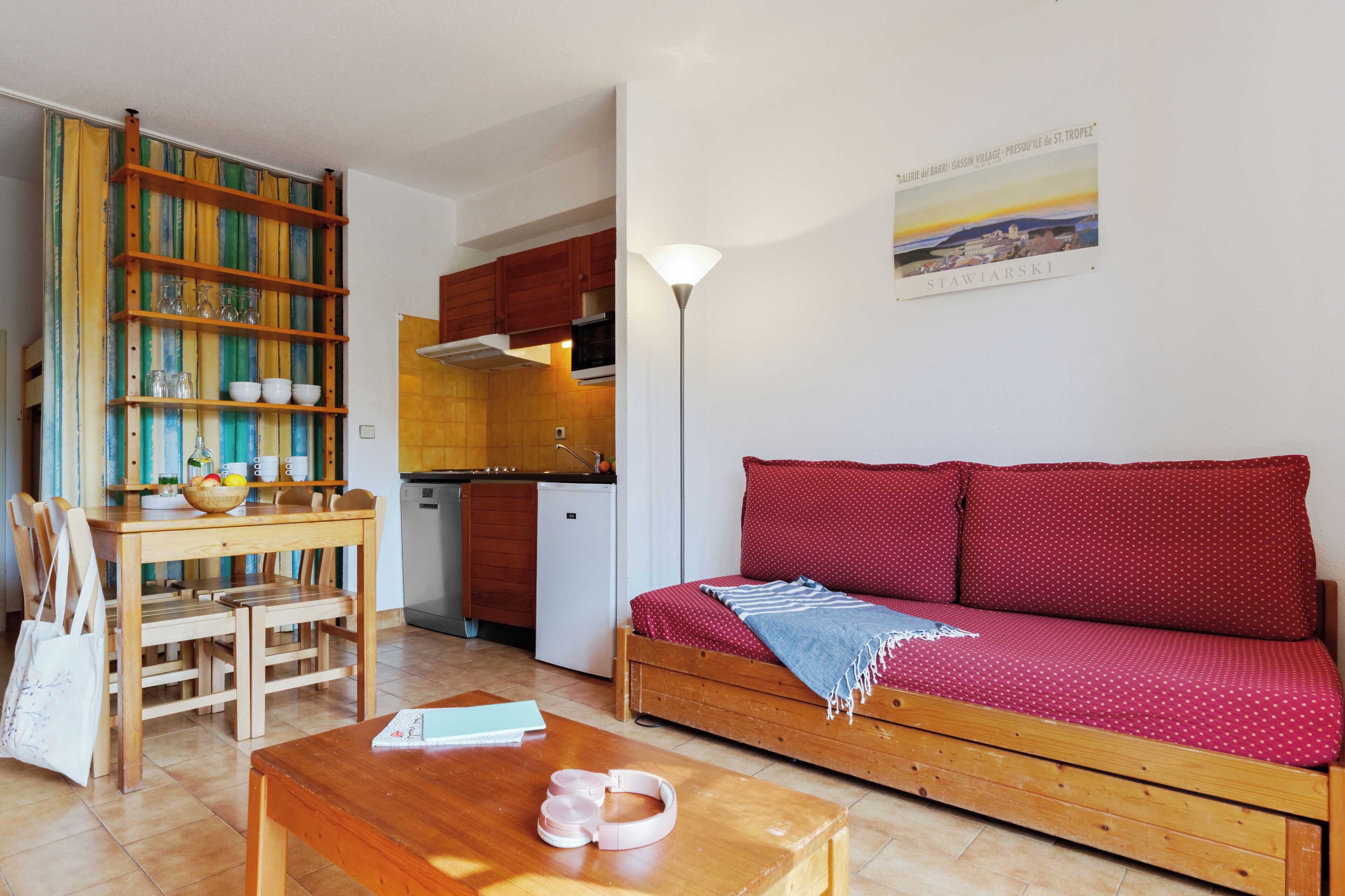 A compact living space with a kitchenette, a dining area, and a sofa with a red polka dot cover.
