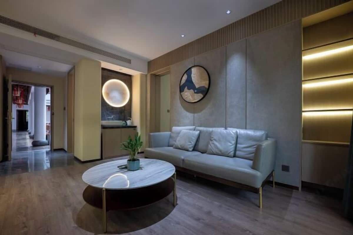 Un salon moderne avec un canapé, une table basse ronde et un luminaire circulaire fixé au mur.