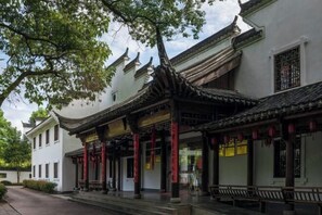 A traditional Chinese building with ornate roof tiles, wooden beams, and red pillars.