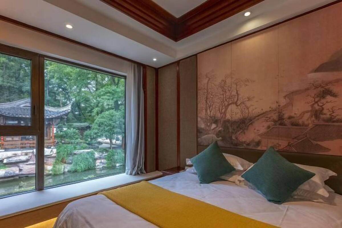 Une chambre d’hôtel avec un lit, une grande fenêtre et un tableau au mur.