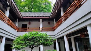 A traditional courtyard with a central tree, wooden railings, and white walls.