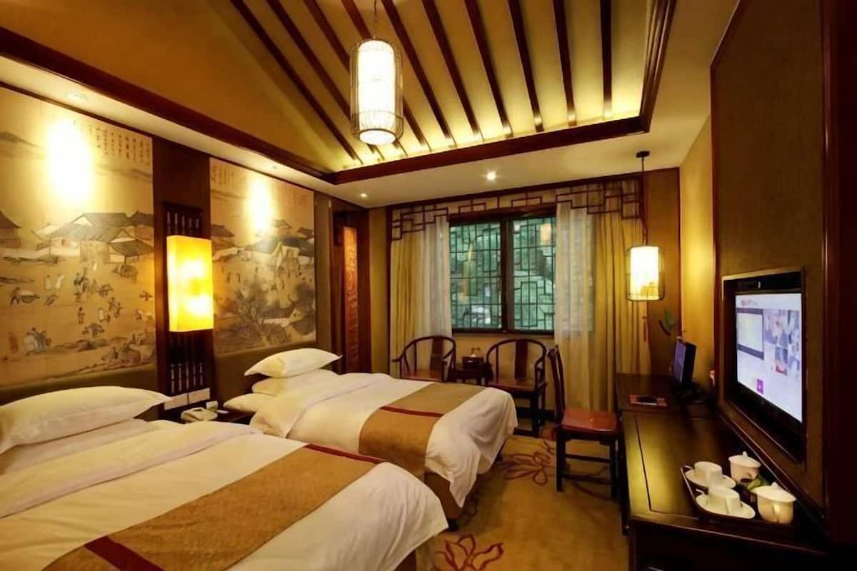 Une chambre d’hôtel avec deux lits, un bureau avec une télévision et un décor traditionnel.