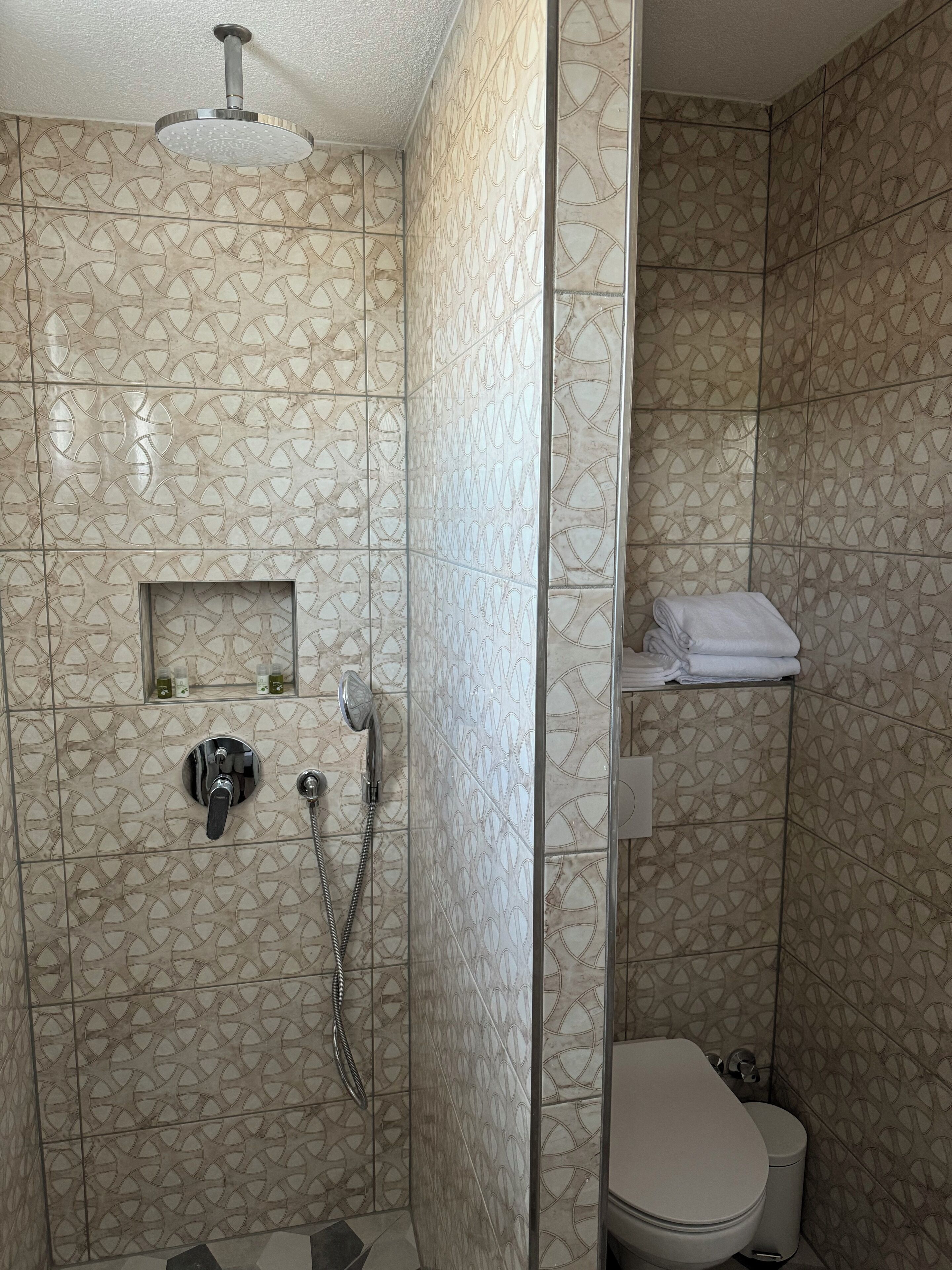 Un baño con ducha, inodoro y toallero.