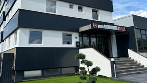 A modern hotel building with a black and white facade, a visible entrance, and a small lawn with trimmed bushes. - Dido Diamond Hotel (Dietzenbach)