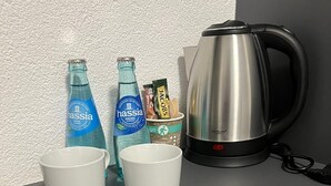 A kitchen counter with a kettle, two cups, and bottles of water. - Dido Diamond Hotel (Dietzenbach)