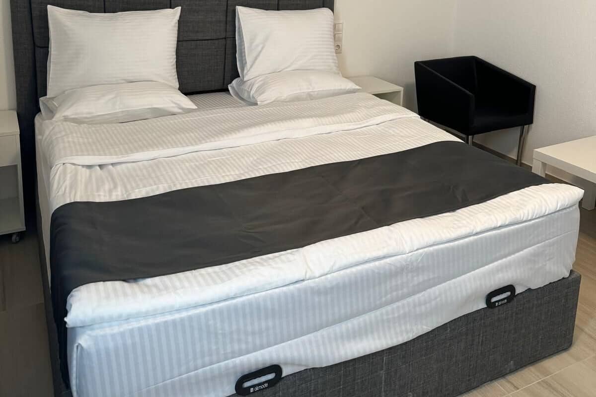 Een moderne slaapkamer met een groot bed, een hoofdeinde, een nachtkastje en een bedtafel.