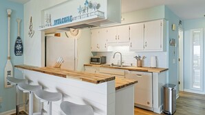 Una cocina con gabinetes blancos, encimera de madera y una zona de bar con taburetes.