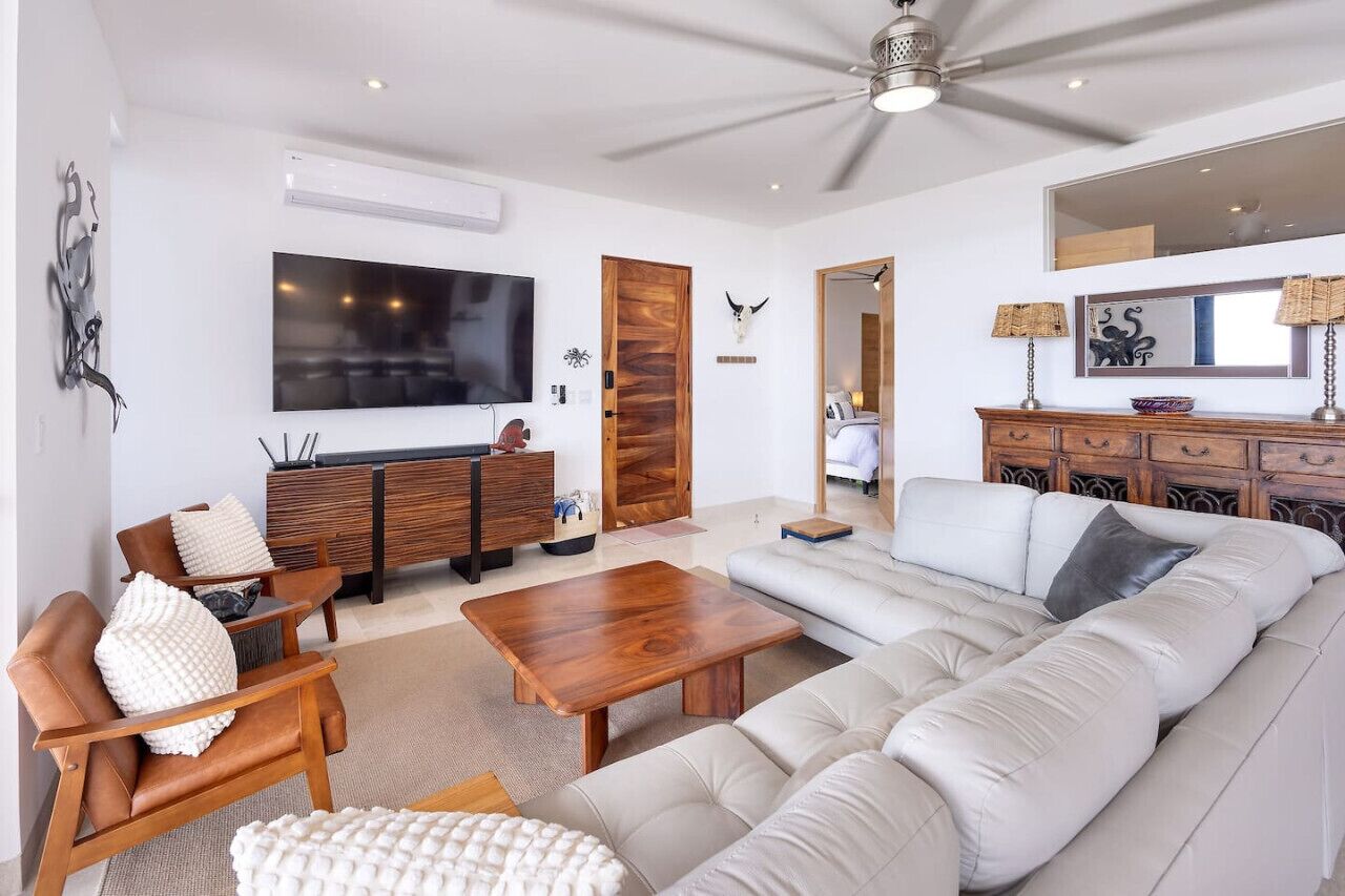 Un salon moderne doté d’un grand téléviseur à écran plat, d’un meuble en bois, d’un canapé et d’une table basse.