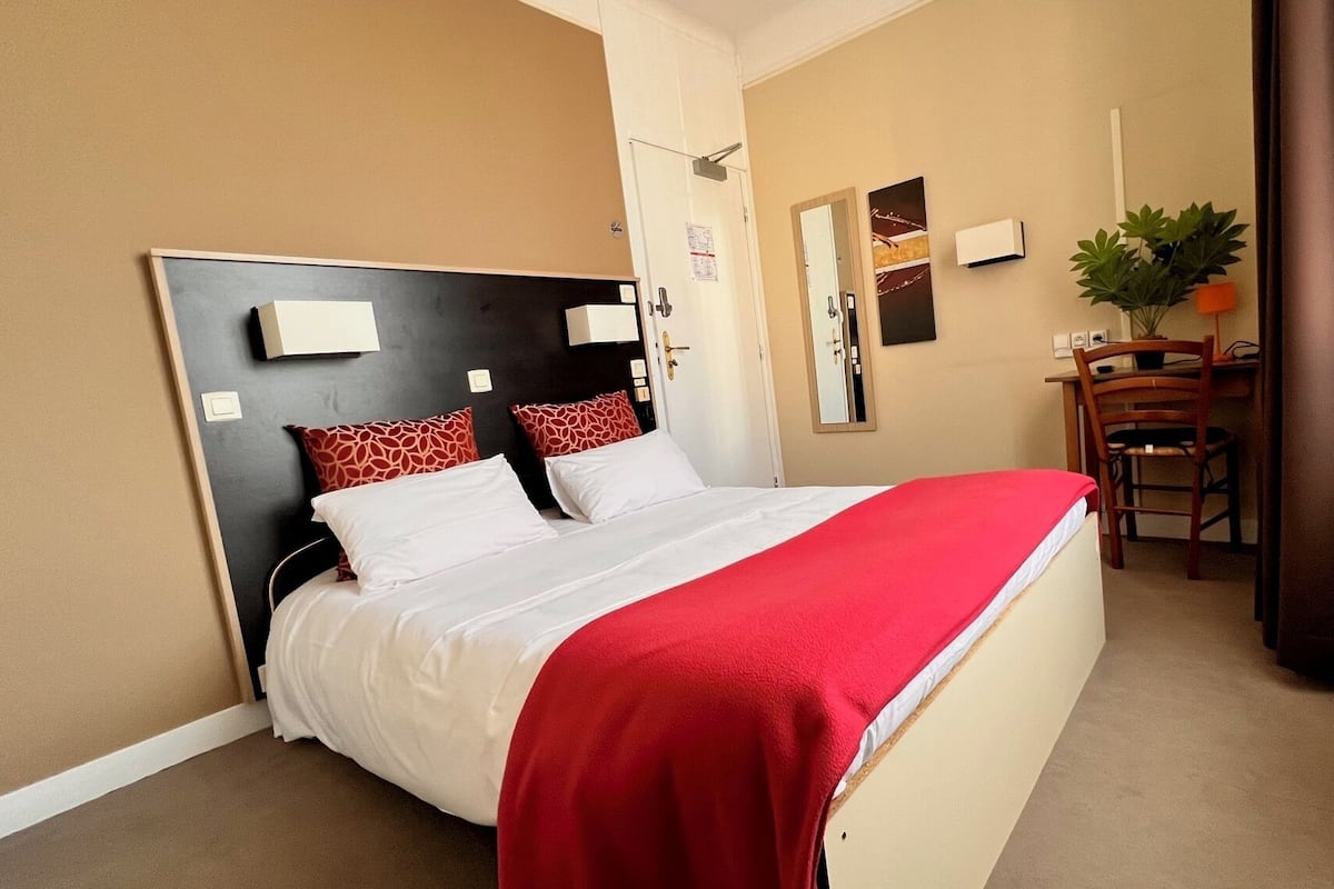 A hotel room with a bed, a desk, and a chair.