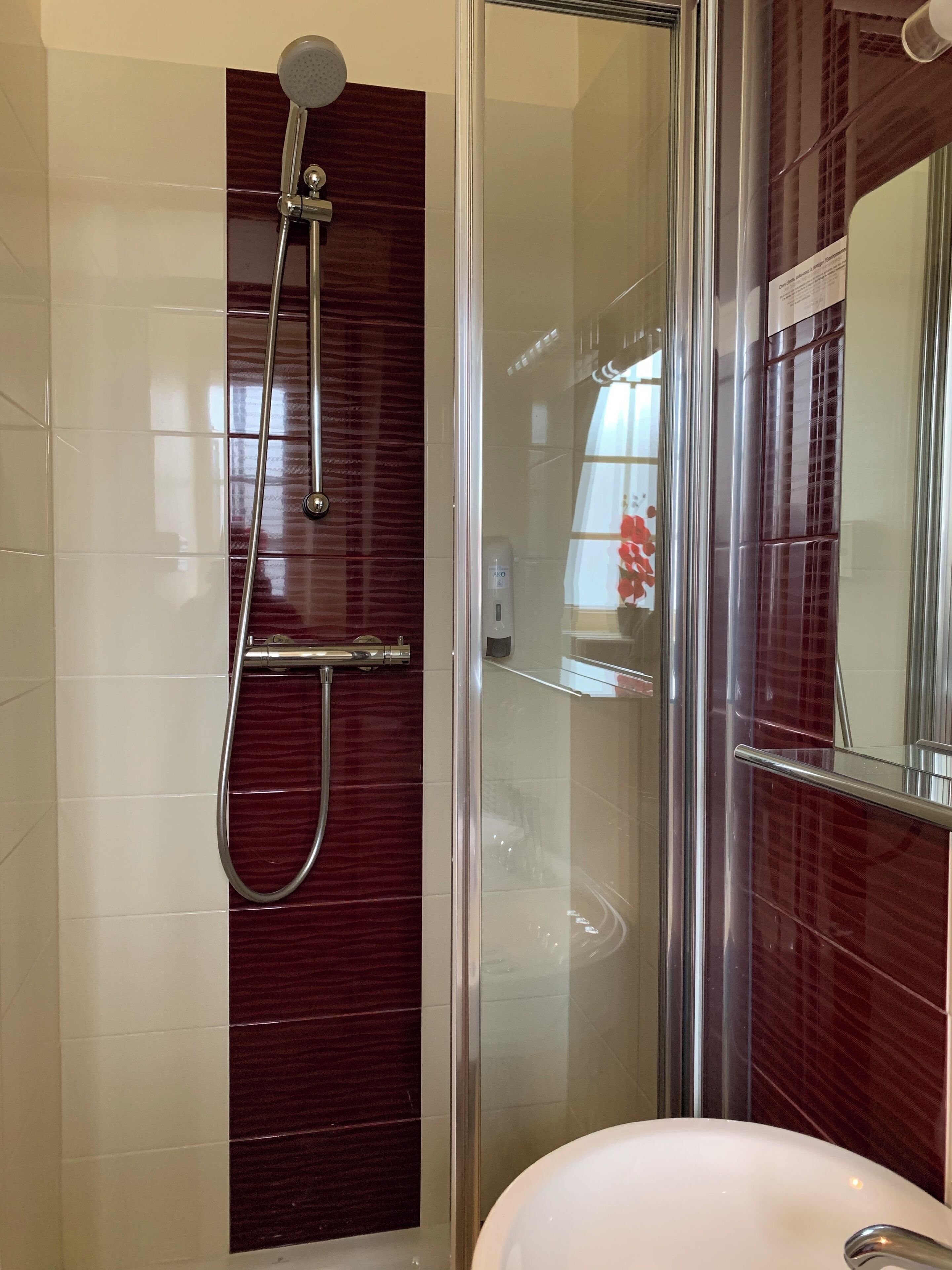 Un baño moderno con ducha de vidrio, lavamanos blanco y espejo.
