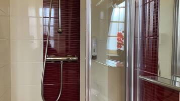 Un baño moderno con ducha de vidrio, lavamanos blanco y espejo.
