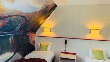 Een hotelkamer met twee bedden, een klein tafeltje en een muurschildering van een brug over een rivier.