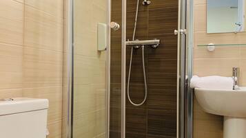 Een moderne badkamer met een douche met glazen wand, een wit toilet en een wastafel met een spiegel erboven.