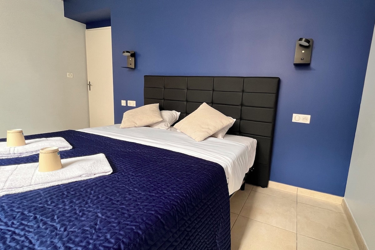 A hotel room with a bed, a blue wall, and a white ceiling.