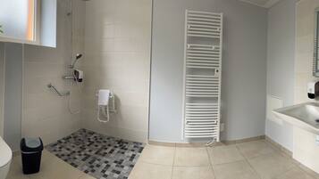 A modern bathroom with a toilet, bidet, shower, and sink.