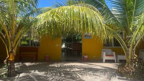 A courtyard with palm trees, a yellow building, and a white chair.