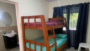 A bunk bed in a room with a sink, mirror, and a window with curtains.
