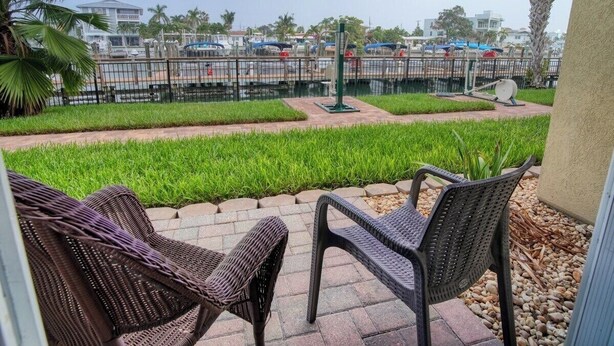 Une terrasse extérieure avec des meubles en osier, un parking en arrière-plan et un ciel dégagé.