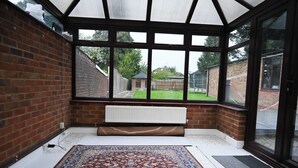 Une véranda avec un tapis à motifs, un radiateur et une vue sur un jardin arrière.