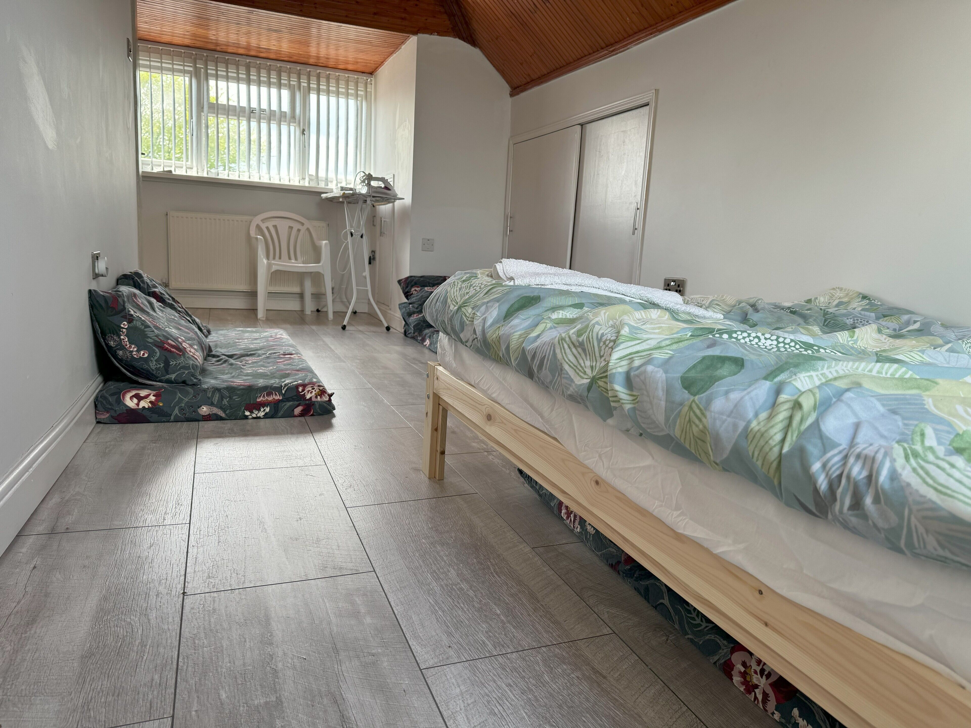 Une chambre à coucher avec un lit, une chaise, un radiateur et une fenêtre avec des stores.