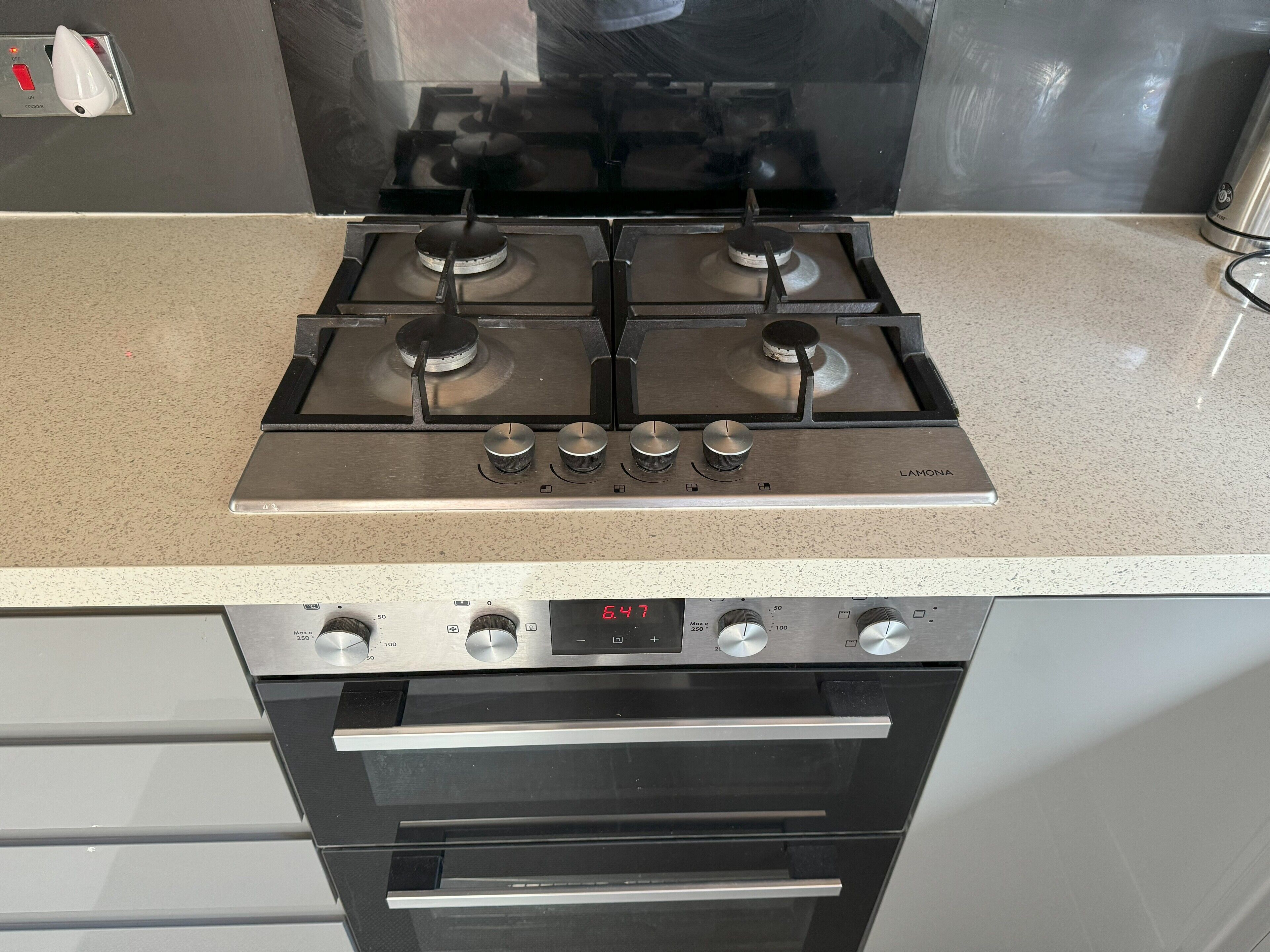 Eine Küche mit einem vierflammigen Herd, einer digitalen Uhr und einem eingebauten Backofen.