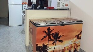 Una cocina compacta equipada con refrigerador, cafetera, microondas y refrigerador-congelador.