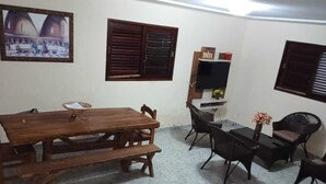 Una habitación con una mesa de comedor de madera, una mesa de billar y un televisor.