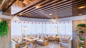 A modern hotel lobby with seating arrangements, a wooden ceiling, and a plant shelf. - Soaring Dragon Tea Culture Hotel (Hanzhong High-speed Railway Station Wanbang Flagship) (Hanzhong)