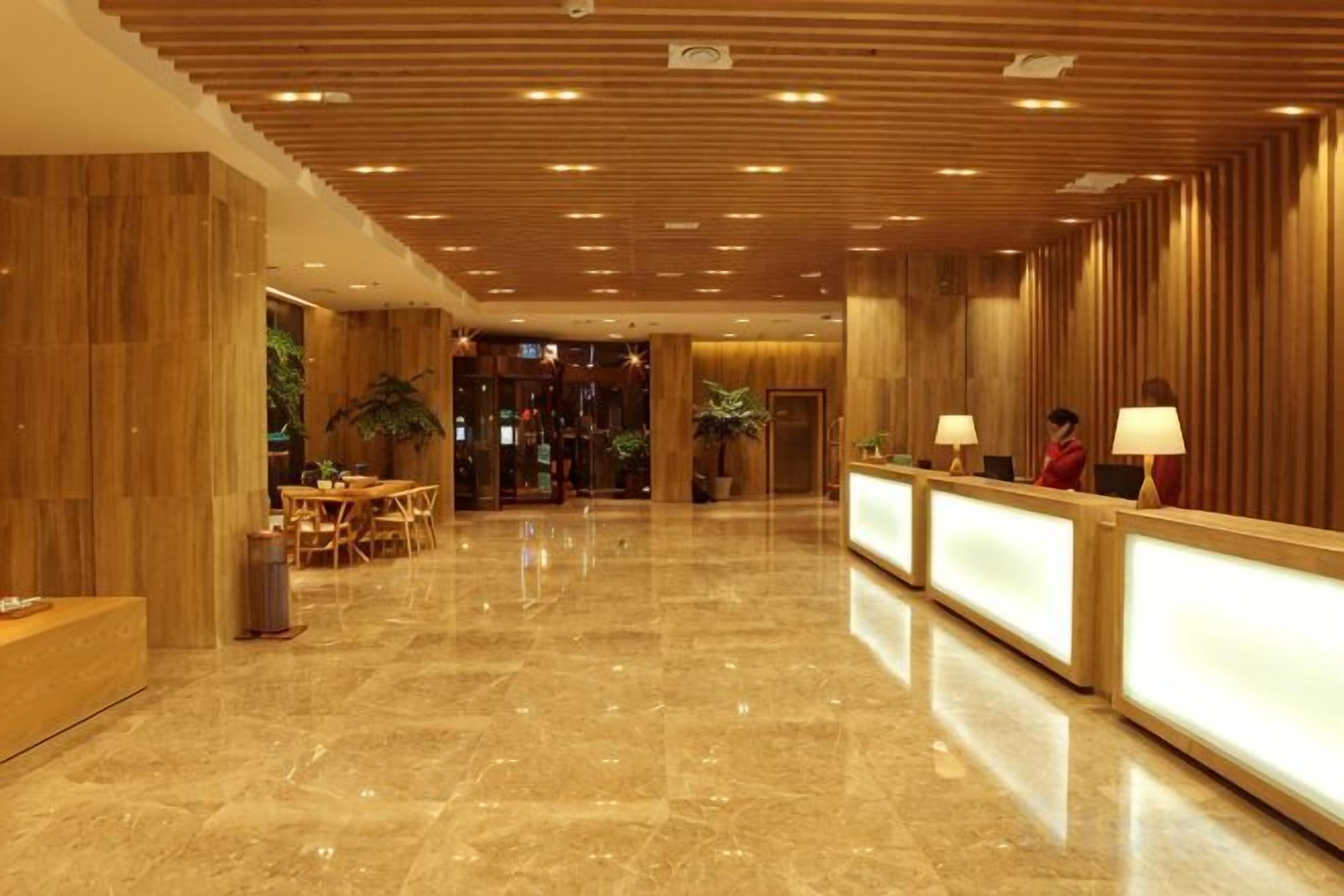 A hotel lobby with a reception desk, seating area, and a polished marble floor.