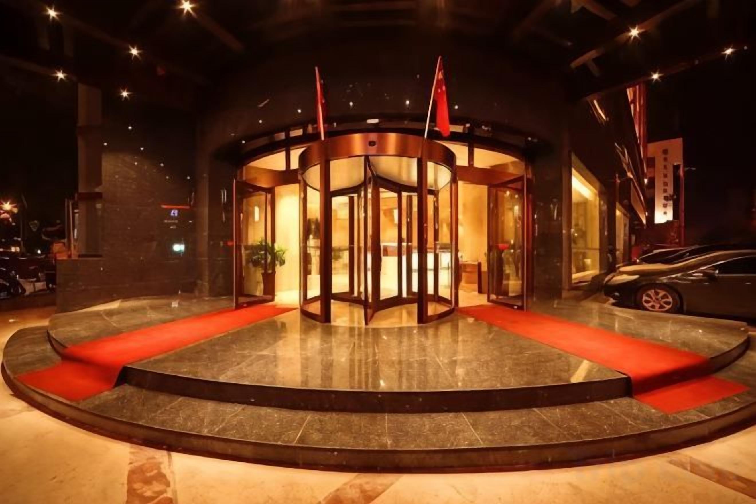 A revolving door entrance with a red carpet leading to a lobby area.