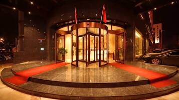 A revolving door entrance with a red carpet leading to a lobby area.